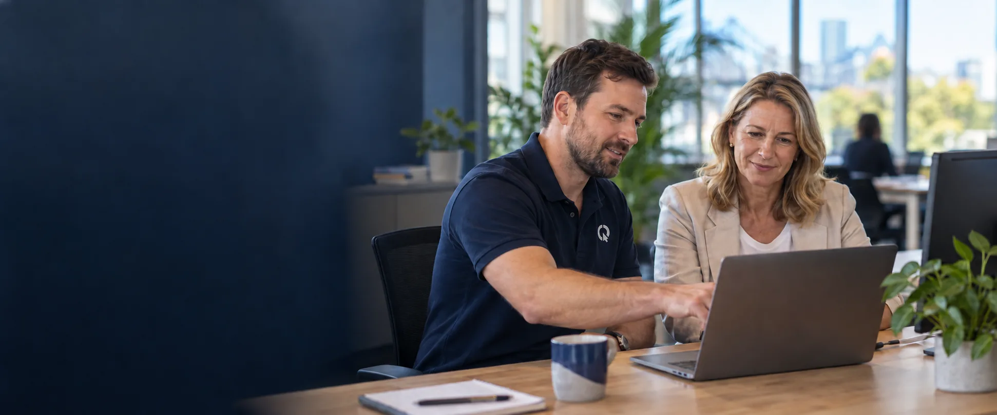 SEQ IT technician helping a client with her laptop at her desk